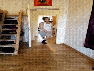 a man in a white tank top is dancing in a room