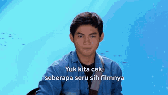 a man in a blue shirt with the words yuk kita cek seberapa seru sih filmnya below him