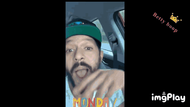 a man with a beard wearing a green hat with monday written on it