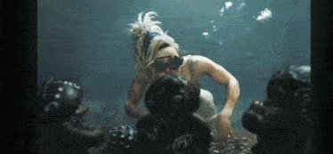 a woman is swimming in the ocean with a group of sea turtles .