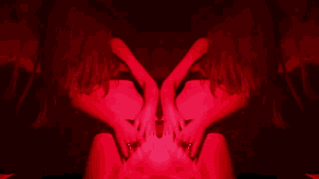 a woman with long red hair is sitting in a dark room with red lights behind her
