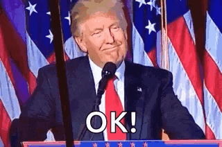 donald trump is giving a speech at a podium in front of an american flag and saying `` ok '' .