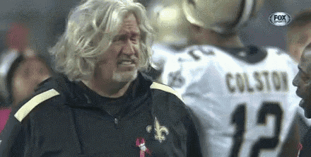 a man with blonde hair and a beard is standing in front of a football player wearing a colston jersey .