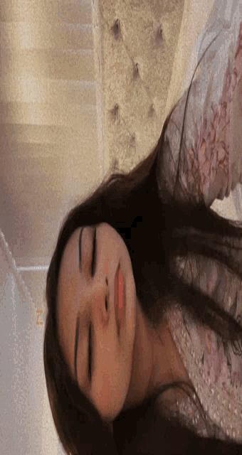 a woman with her eyes closed is wearing a floral top
