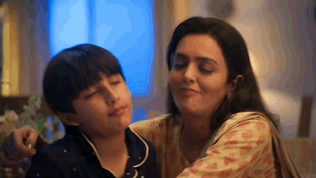 a woman is petting a young boy on the cheek