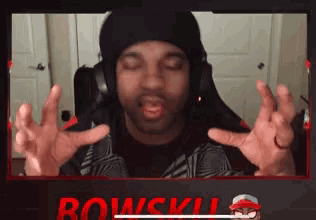 a man wearing headphones and a hat is sitting in front of a screen that says bowskill