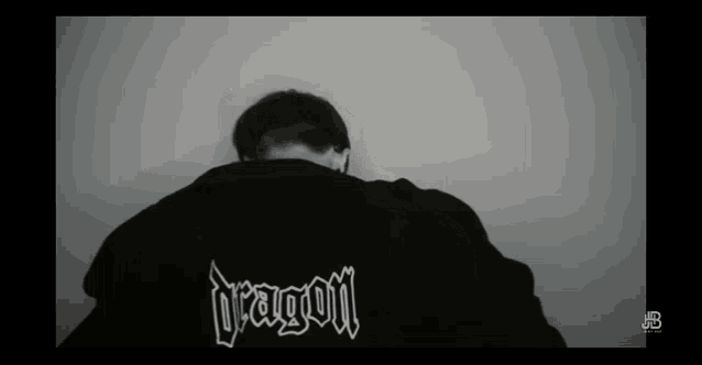 a black and white photo of a man wearing a jacket that says dragon
