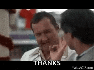 two men are talking to each other in a store and one of them is giving a thumbs up sign .