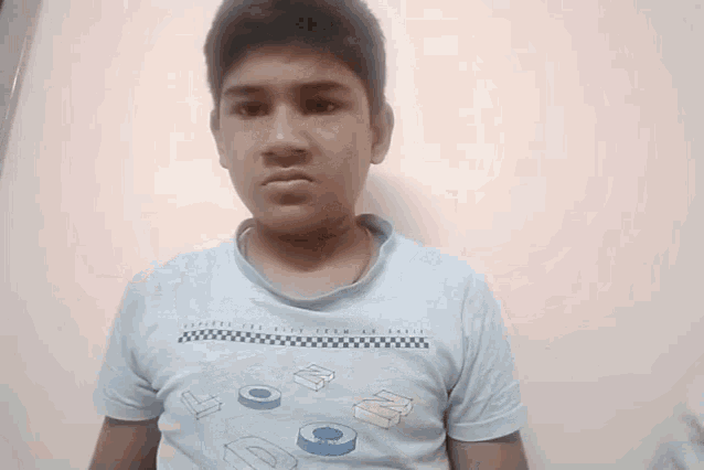 a young boy wearing a blue shirt with the letters dc on it makes a funny face