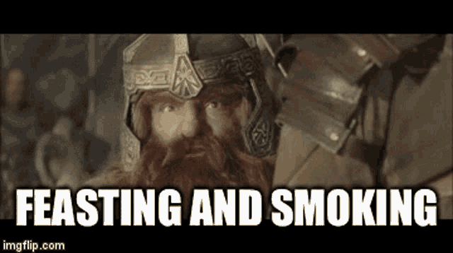 a bearded man wearing a helmet and armor is standing next to another man with the words feasting and smoking .
