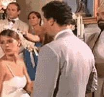a bride and groom are standing next to each other in front of a crowd of people at a wedding reception .