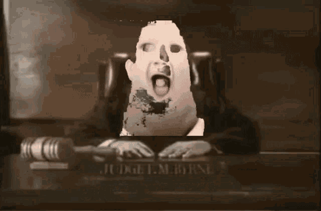 judge f.m. byrne is sitting at a desk with a picture of a person behind him