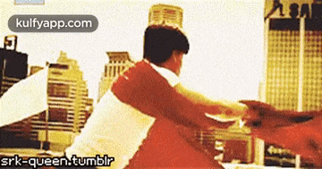 a man in a white shirt is holding a red object in front of a city skyline ..