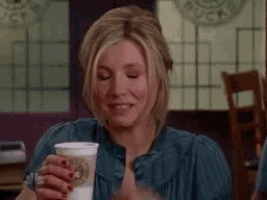 a woman is holding a cup of coffee and smiling .