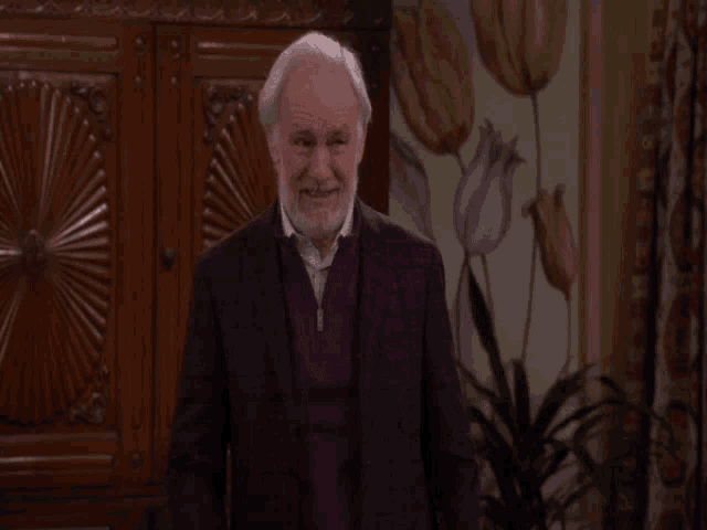 an elderly man with a beard is pointing at the camera