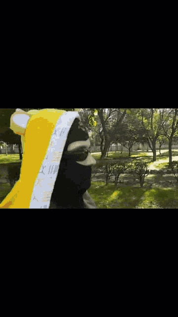 a person wearing a black mask and a yellow hoodie
