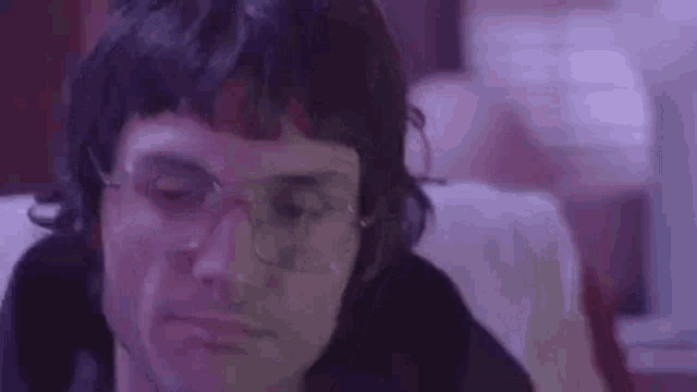 a man wearing glasses and a wig is sitting in a chair .