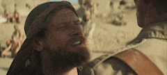 a man with a beard is standing next to another man in a desert .