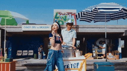 a man and a woman standing in front of a candy deli and grocery store