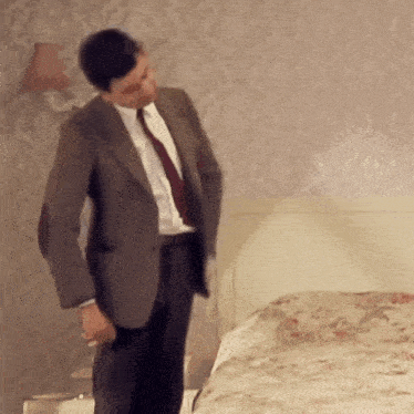 a man in a suit is standing in front of a bed