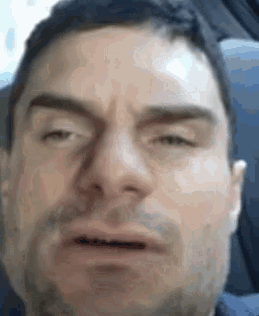 a man with a beard is making a funny face with his eyes closed .