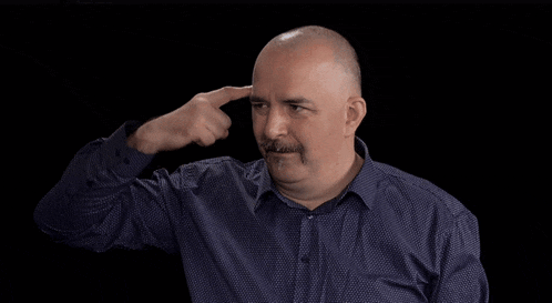 a man with a mustache is making a funny face with his finger to his ear