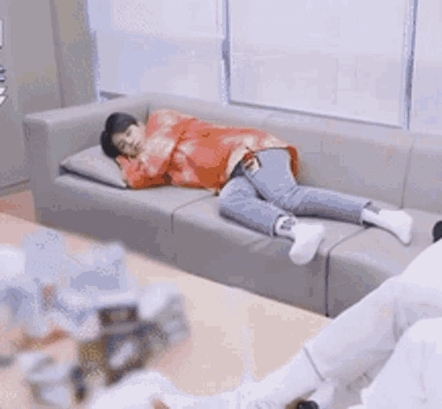 a group of people are laying on a couch playing with pillows