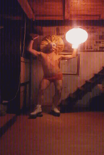 a man in red underwear is standing in a dark room with stairs in the background
