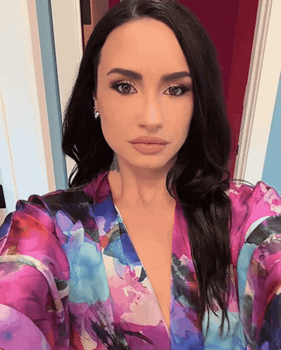a woman taking a selfie in a purple floral top