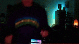 a blurry picture of a person in a dark room with a rainbow shirt on