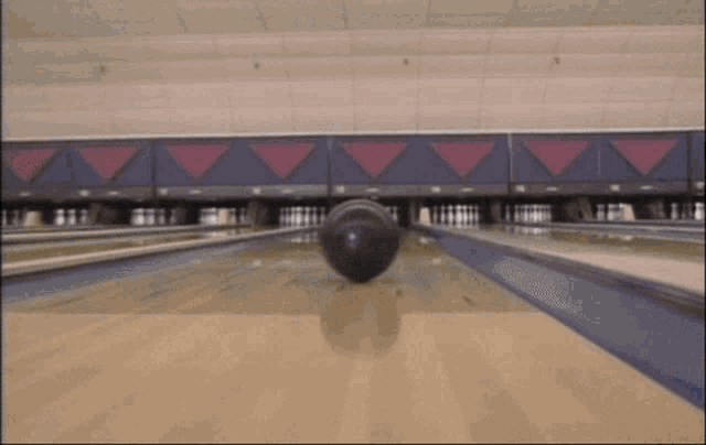 a bowling ball is going down a bowling alley with red triangles on the wall