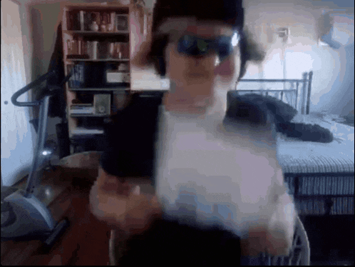 a man wearing sunglasses and headphones stands in a bedroom