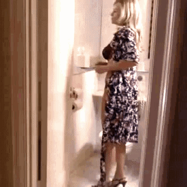 a woman in a dress is standing in a bathroom