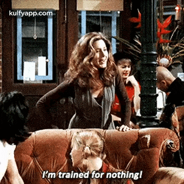 a woman is sitting on a couch talking to another woman while another woman looks on .