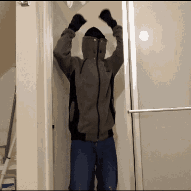 a man in a hoodie is standing in a doorway with his arms up