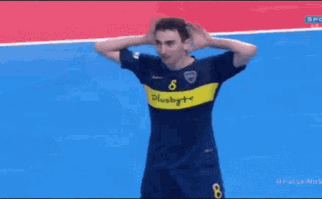 a man wearing a blue and yellow jersey with the number 8 on it covering his ears