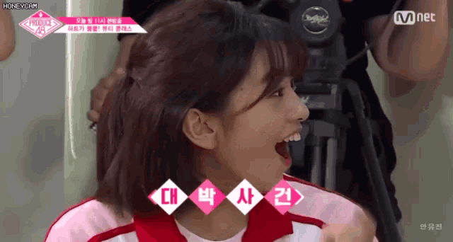a girl is laughing in front of a camera with the letters mnet on it