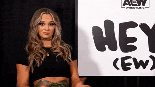 a woman is standing in front of a sign that says hey ( ew )