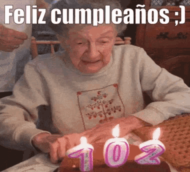an elderly woman is blowing out candles on a birthday cake