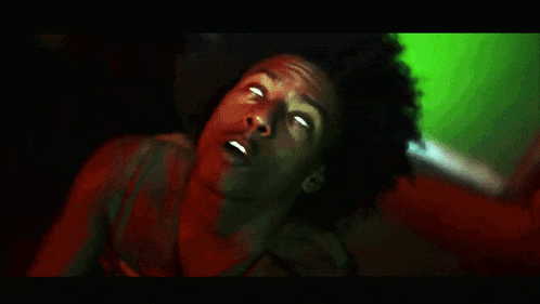 a man with curly hair is laying down with his eyes closed