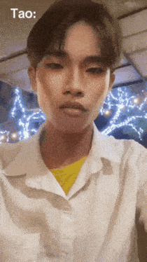 a young man in a white shirt with a yellow shirt underneath is taking a selfie with the words tao above him