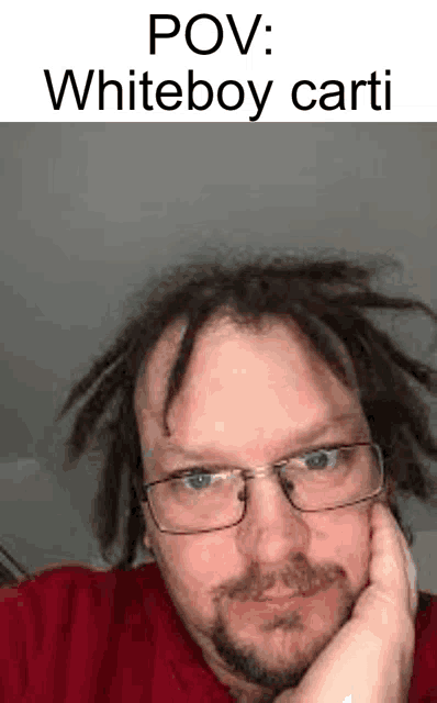a man with dreadlocks and glasses is wearing a red sweater and a red shirt .