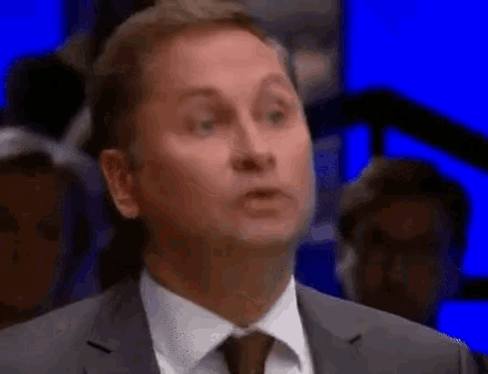 a man in a suit and tie is standing in front of a crowd .
