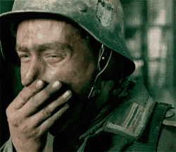 a soldier is covering his mouth with his hand while wearing a helmet .