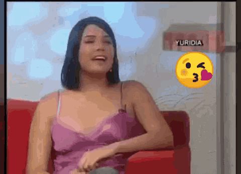 a woman in a purple dress sits on a red couch with a yellow smiley face behind her that says yuridia