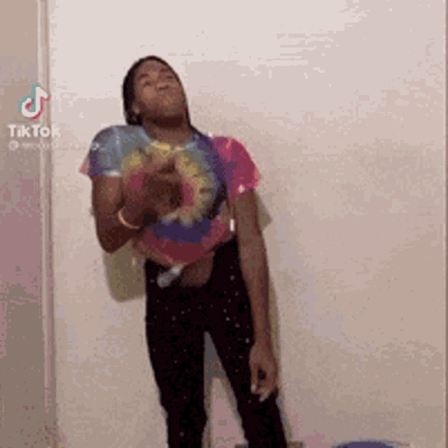 a person wearing a tie dye shirt is standing in front of a wall .