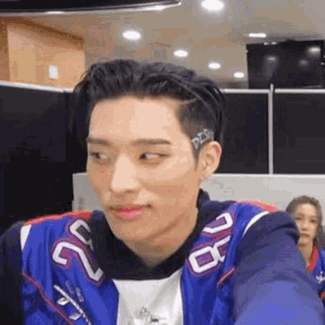 a young man is making a funny face while wearing a blue jacket and a headband .