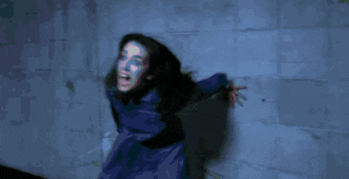 a woman with purple hair is screaming with her mouth open