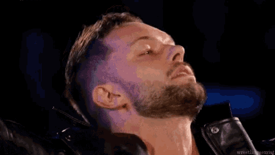 a man with a beard wearing a leather jacket is looking down .