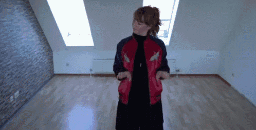 a woman in a red jacket is standing in a room